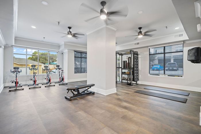 Bright and modern fitness center with cycling equipment, weight training area, and large windows offering natural light.