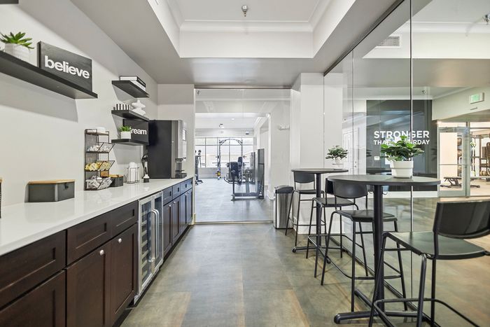 Modern communal area with sleek countertops and vibrant decor connecting to a well-equipped fitness center.