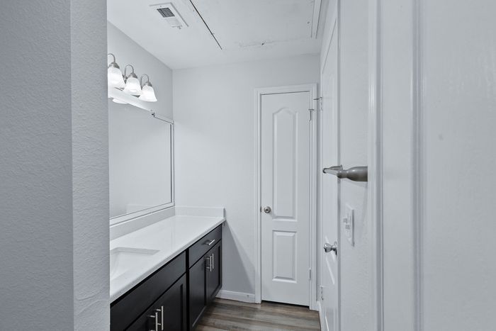 Sleek modern bathroom with elegant white countertop, sophisticated lighting, and stylish cabinetry.