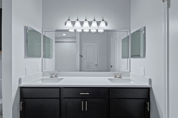 Modern bathroom with elegant dual sinks, stylish mirrors, and chic lighting, offering a luxurious and contemporary feel.