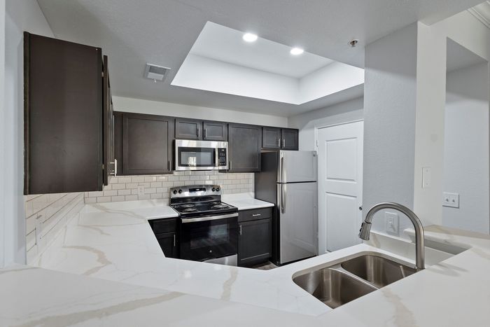 Modern kitchen with sleek stainless steel appliances, dark wood cabinets, and elegant marble countertops, complete with a cozy breakfast bar.