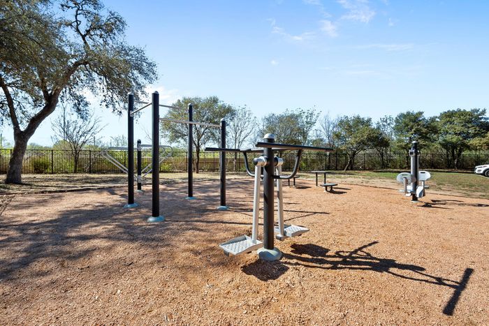 Inviting outdoor fitness area surrounded by nature, featuring modern exercise equipment under a clear blue sky.
