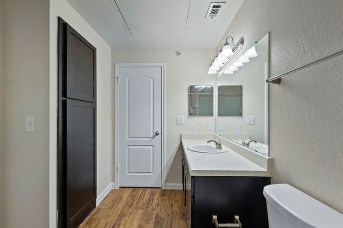 Modern bathroom with elegant vanity mirror, stylish lighting, and sleek wooden flooring.