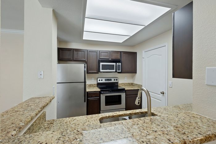Modern kitchen with sleek stainless steel appliances, elegant granite countertops, and rich dark wood cabinetry.