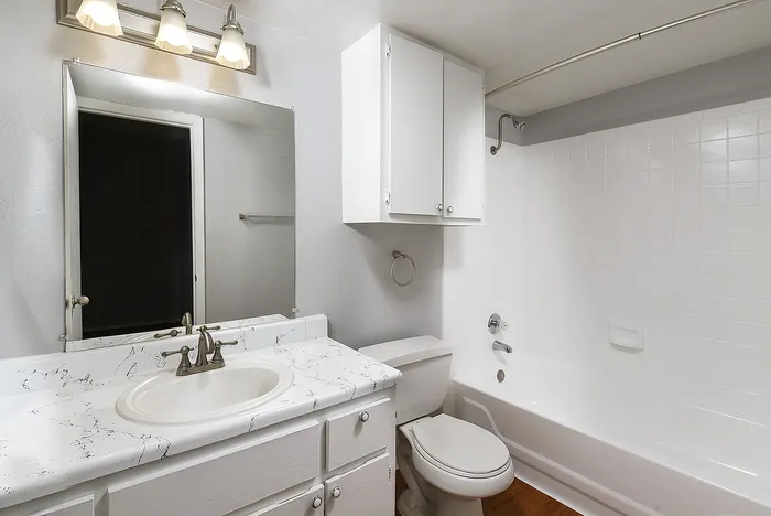 Bright, modern bathroom featuring elegant fixtures, a sleek marble countertop, and a pristine bathtub with white tile walls.