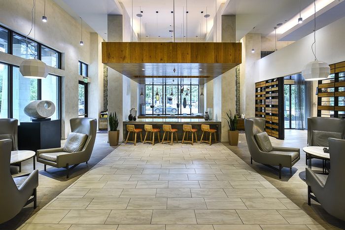 Chic apartment lobby with modern seating, high ceilings, and expansive windows providing natural light.
