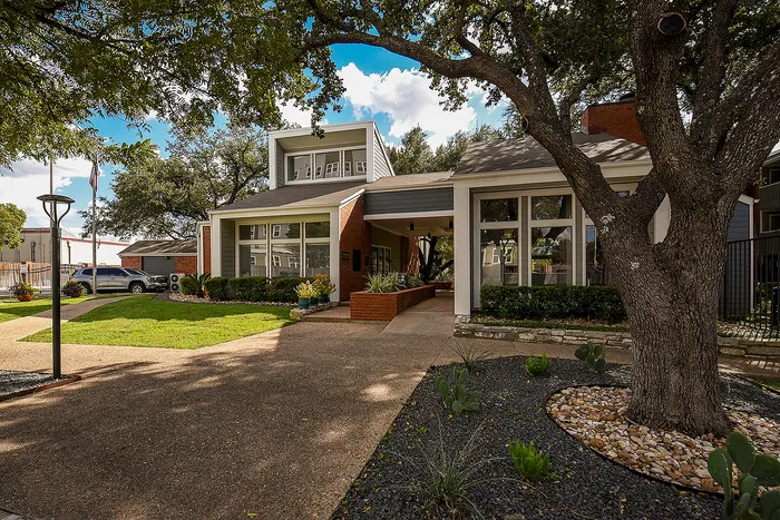 Charming residential property featuring a modern facade, lush landscaping, and a welcoming pathway under a gorgeous tree.