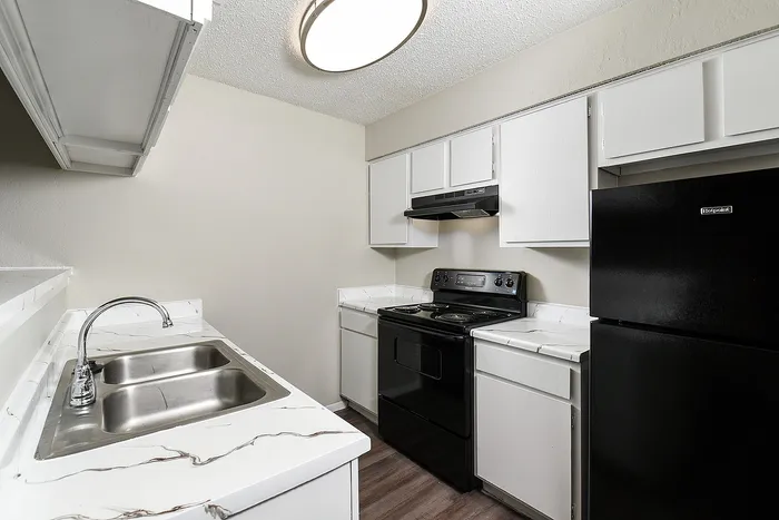 Modern kitchen with sleek black appliances, elegant white cabinetry, and a stylish marble-look countertop, perfect for home chefs.