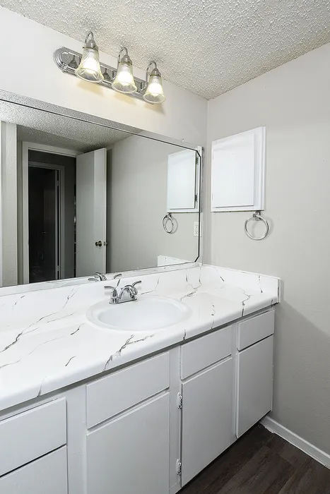 Elegant bathroom featuring a modern vanity with marble-style countertop, large mirror, and stylish light fixtures.