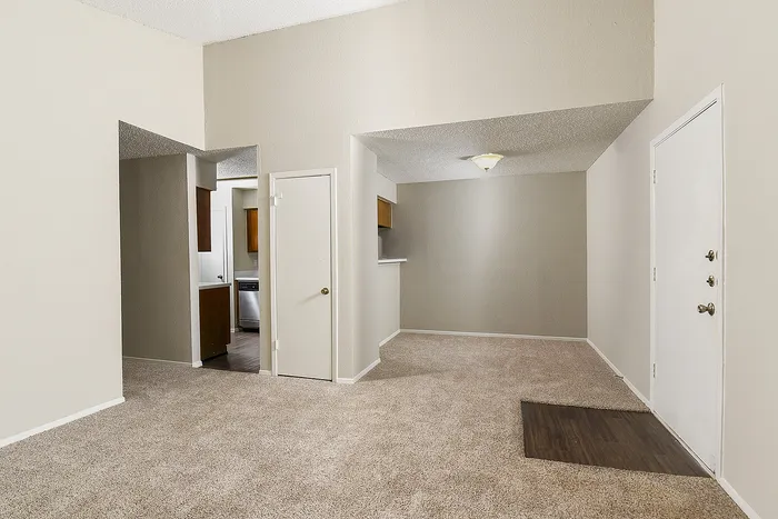 Inviting apartment interior with neutral carpeting, cozy dining nook, and a glimpse of the modern kitchen.