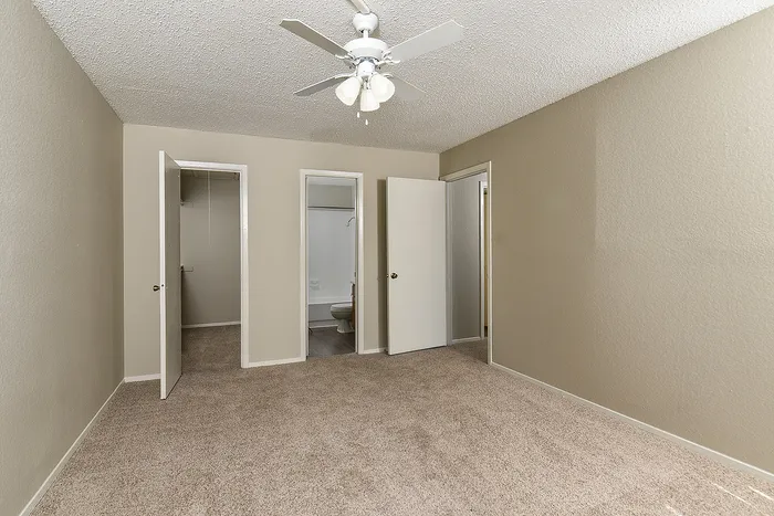 Bright and spacious bedroom with cozy carpet flooring and modern ceiling fan.