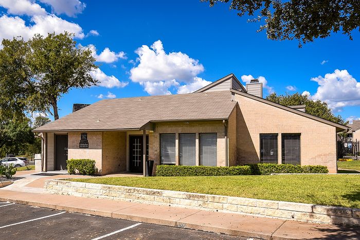 Charming brick building with manicured landscaping under a vibrant blue sky, perfect for future residents seeking a welcoming community.