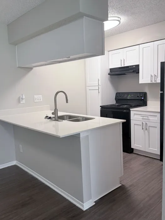 Modern kitchen with sleek white cabinets, dark appliances, and a stylish breakfast bar in a contemporary apartment.