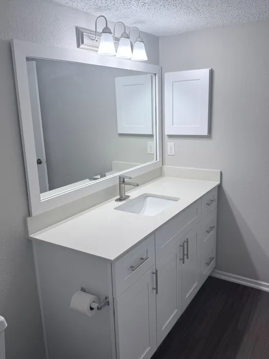 Elegant bathroom with a sleek white vanity, polished countertop, and stylish mirrored lighting.