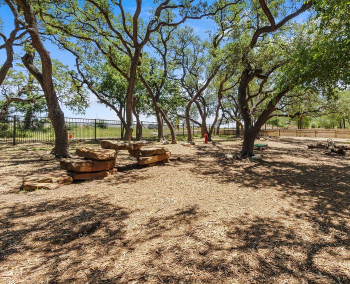 Charming outdoor space with rustic stone seating, shaded by mature trees, ideal for relaxation and gatherings.