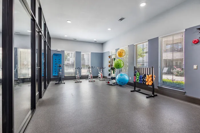 Bright and modern gym featuring exercise bikes, stability balls, and vibrant weights, ideal for a refreshing workout.