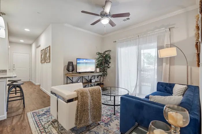 Inviting living room with a plush blue sofa, modern decor, and natural light streaming through sheer curtains.