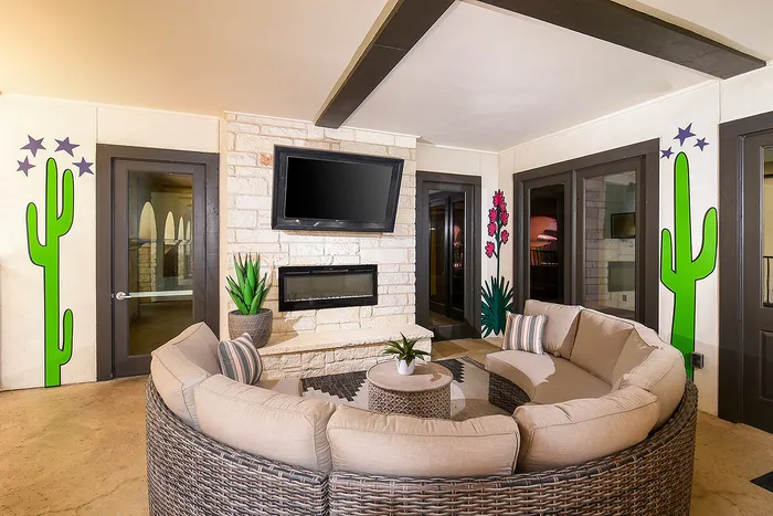 Chic living room featuring a cozy curved sofa, stylish stone fireplace, and vibrant cactus wall art, perfect for relaxation and entertaining.