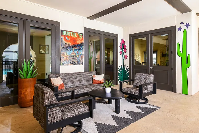 Chic outdoor seating area with modern wicker furniture and vibrant Austin-themed artwork, perfect for relaxation.