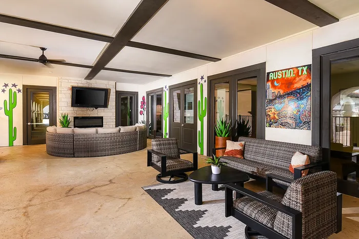 Chic patio lounge featuring stylish wicker furniture, vibrant cactus artwork, and a cozy entertainment area with a modern TV in Austin, TX.