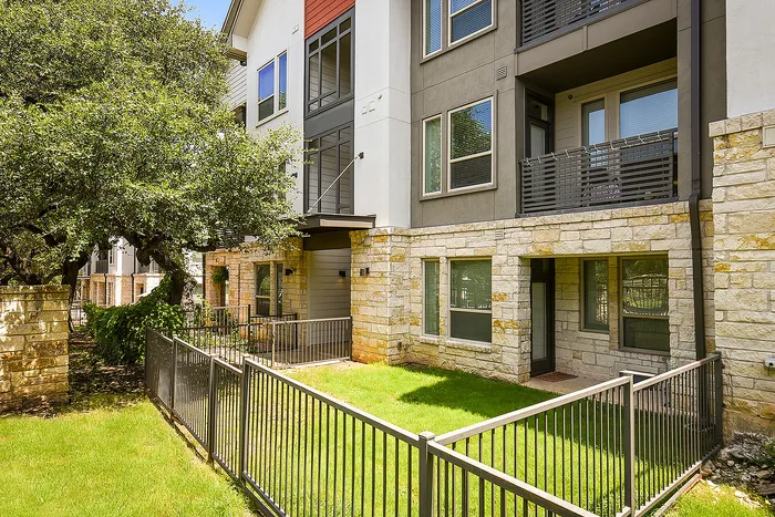 Charming modern apartment exterior with stone accents, private balconies, and lush greenery.