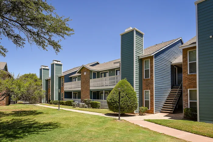 Charming apartment complex displaying modern architecture with vibrant blue siding, well-maintained greenery, and inviting balconies.