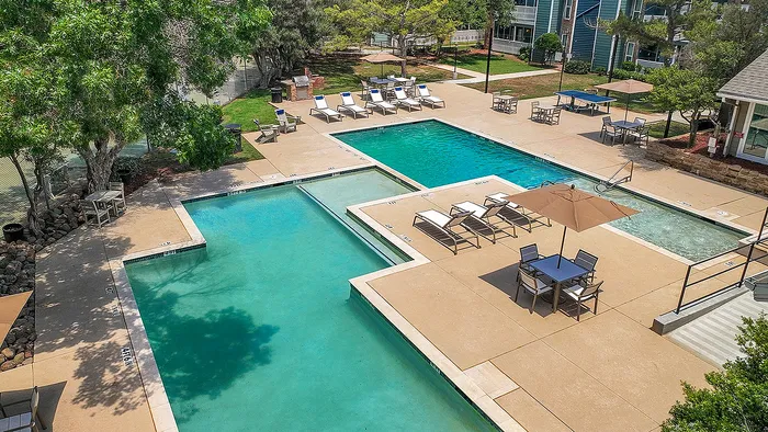 Luxurious outdoor pool area with multiple pools, sun loungers, shaded seating, and lush greenery, perfect for relaxation and leisure.