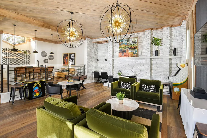 Chic reading area with lush green velvet chairs, stylish lighting, and modern decor accents, perfect for relaxation and work.