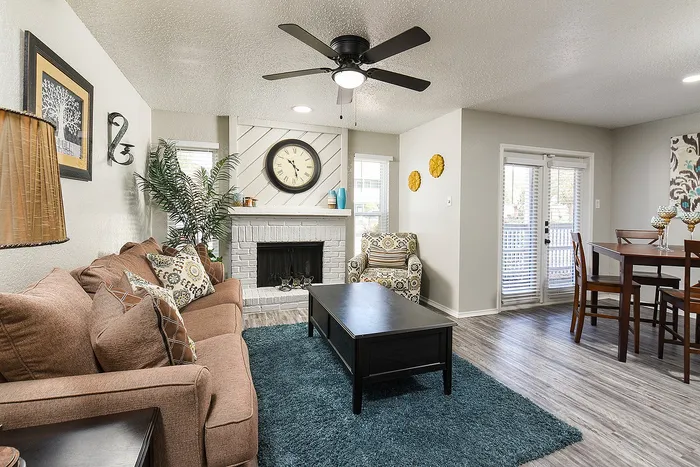 Inviting living area with cozy sofas, modern ceiling fan, elegant fireplace, and natural light from French doors.