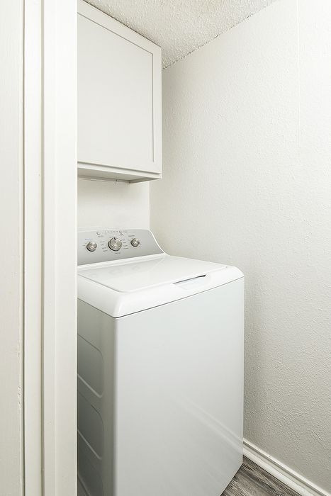 Compact laundry nook featuring a modern washer and overhead storage, maximizing convenience and space efficiency.