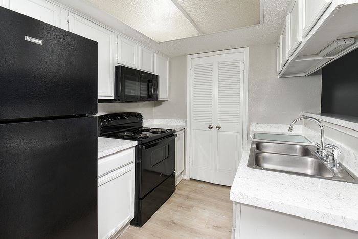 Modern kitchen with sleek black appliances, polished countertops, and ample white cabinetry.