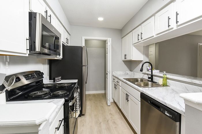 Modern kitchen with sleek stainless steel appliances, elegant marble countertops, and pristine white cabinetry.