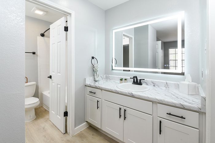 Elegant bathroom with modern design, featuring a luminous LED mirror, sleek marble countertop, and stylish white cabinetry.