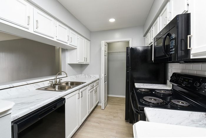 Sleek kitchen showcasing modern black appliances, elegant marble countertops, and ample white cabinetry.