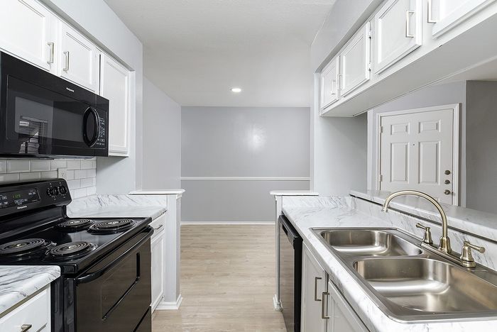 Modern kitchen with sleek black appliances, elegant marble countertops, and ample cabinet space, showcasing a bright and inviting atmosphere.