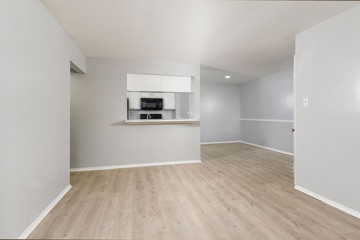 Bright open-concept living area with elegant wood flooring and a stylish kitchen passthrough window.
