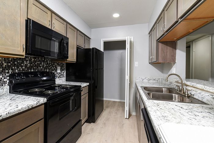 Modern kitchen with sleek black appliances, elegant granite countertops, and stylish wood cabinets.