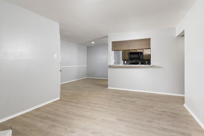 Modern open-concept apartment with elegant wood flooring, spacious living area, and a chic kitchen view.