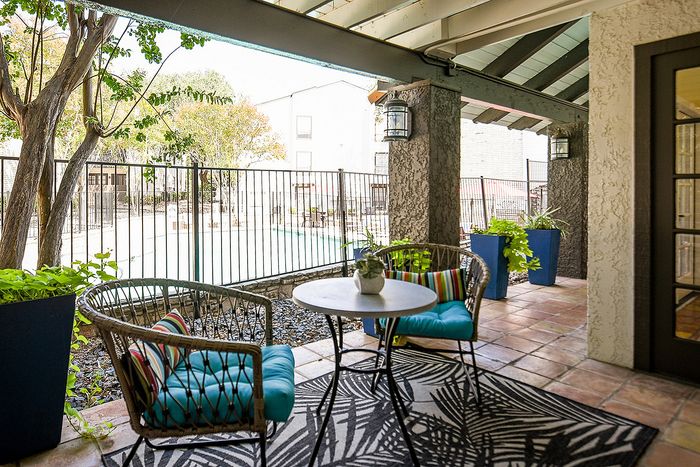 Charming outdoor patio with cozy seating and a lush view of the pool, framed by vibrant plants for a relaxing retreat.