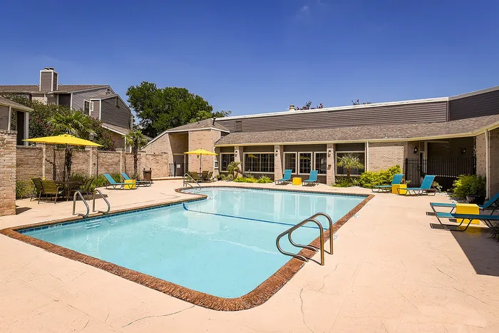 Inviting outdoor pool area with vibrant loungers and umbrellas, surrounded by lush greenery, perfect for relaxation and socializing.