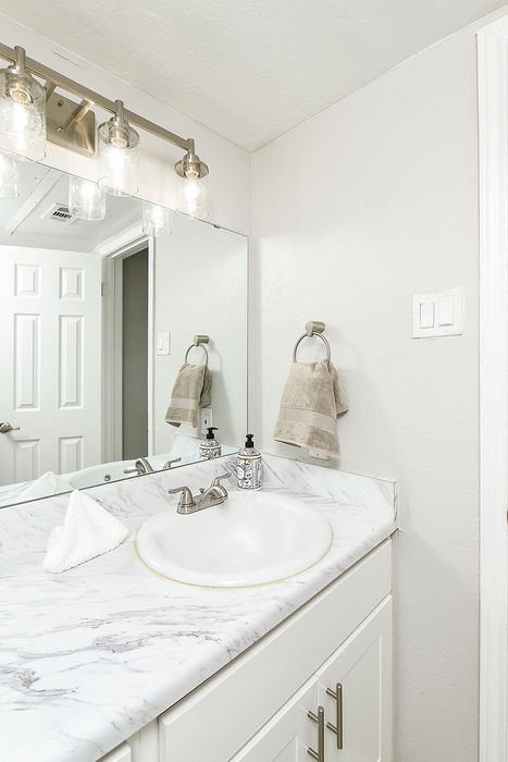 Modern bathroom with elegant marble countertop, sleek fixtures, and ample lighting, offering a pristine and inviting space.