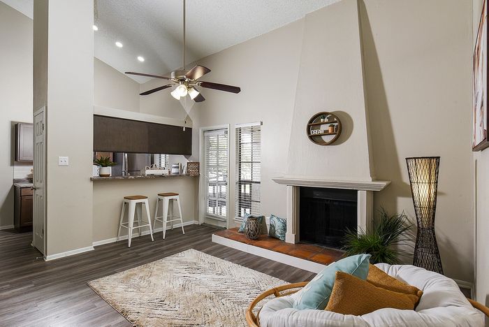 Inviting living room with vaulted ceiling, cozy fireplace, and bar-style kitchen counter complemented by modern seating.