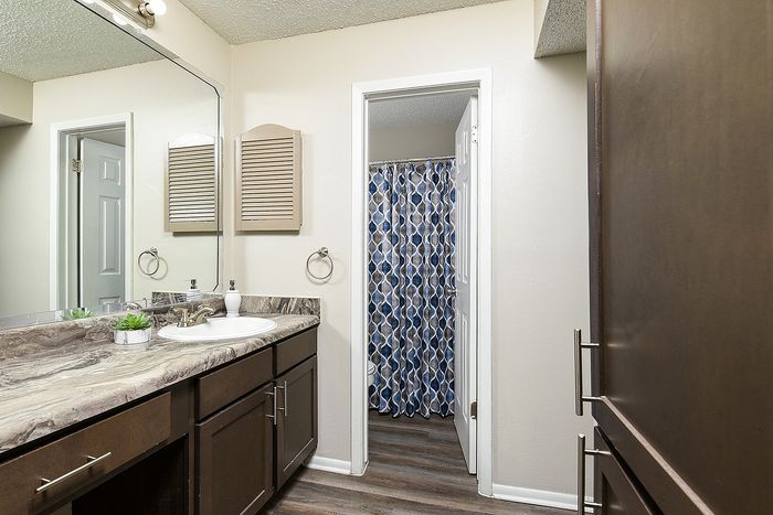Modern bathroom with elegant dark wood cabinets, a chic marble countertop, and contemporary fixtures, showcasing a stylish shower curtain design.