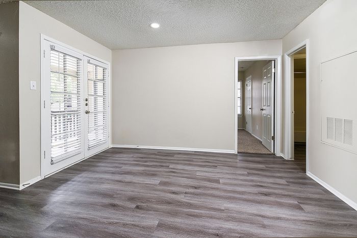 Inviting living space with elegant wood flooring and modern French doors leading to a serene outdoor area.
