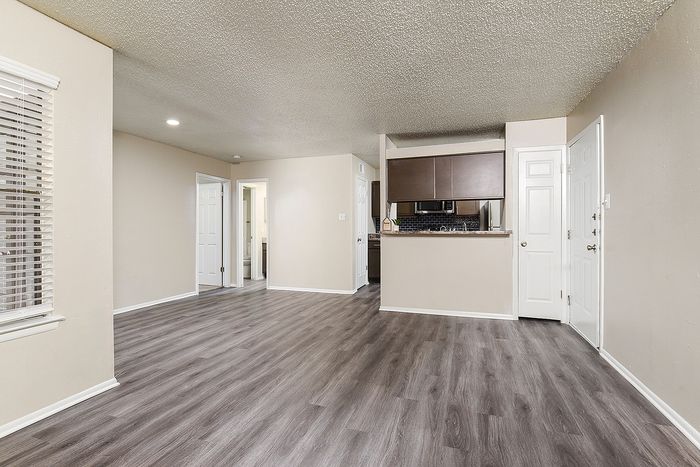 Modern apartment interior with elegant wooden flooring, sleek kitchen, and bright natural lighting.