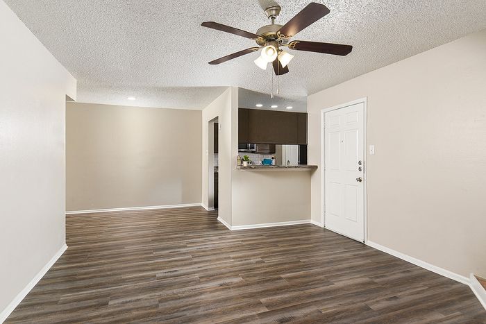 Inviting open-layout apartment with stylish wood flooring, modern ceiling fan, and a cozy kitchen nook perfect for entertaining.