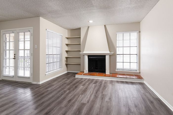 Charming living room with modern hardwood floors, elegant corner fireplace, and abundant natural light from large windows.