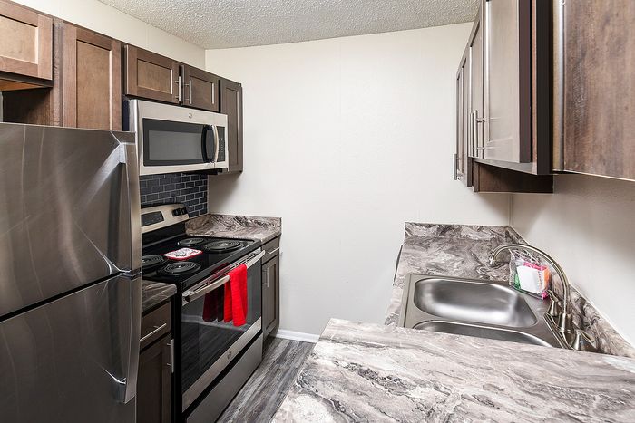 Modern kitchen with sleek stainless steel appliances, elegant dark wood cabinets, and stylish marble countertops.