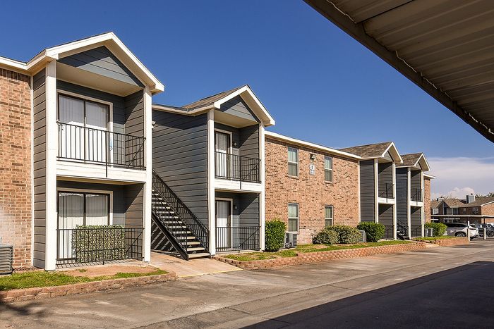 Modern apartment building featuring stylish brick and siding facade with charming balconies and well-maintained surroundings.