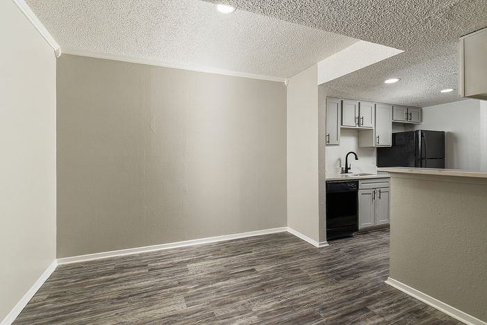 Modern apartment with sleek open-concept kitchen, stylish cabinetry, dark appliances, and elegant wood-style flooring.